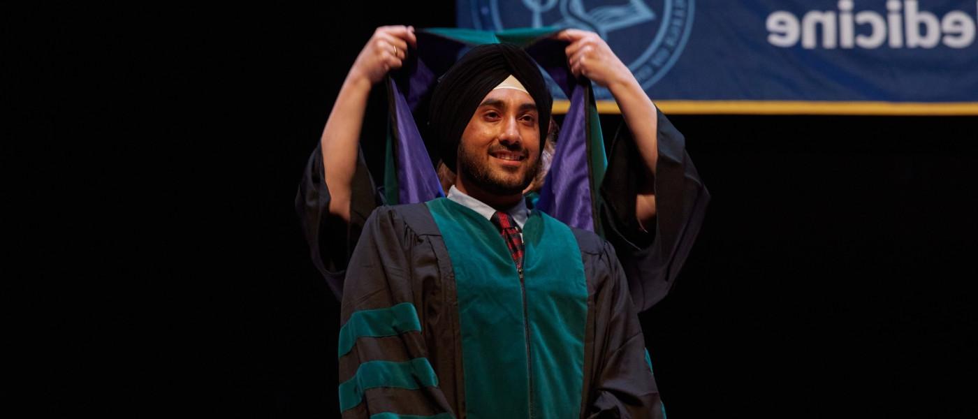 A UNE COM graduate gets hooded at Merrill Auditorium in Portland