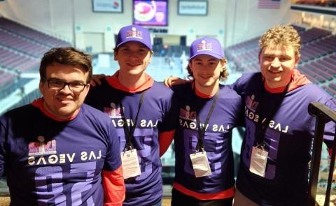 Four students pose wearing NFL-themed shirts